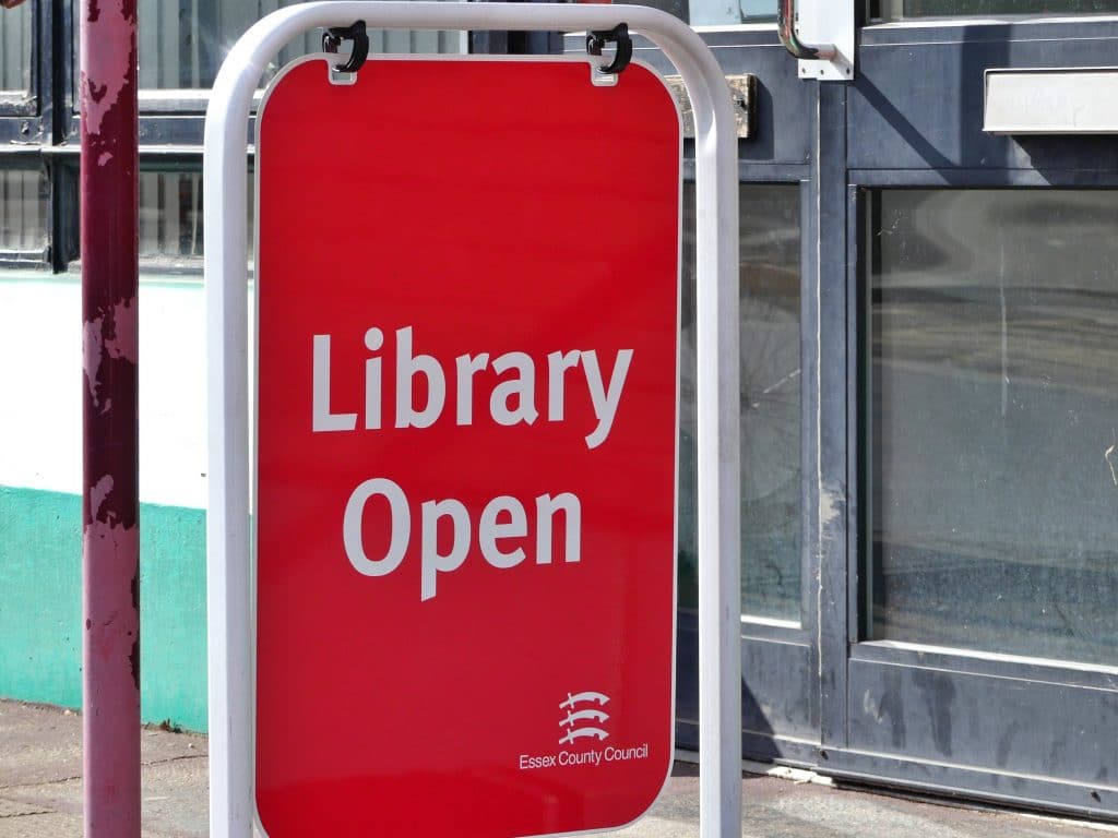 A red 'library open' sign at the entrance to a library.