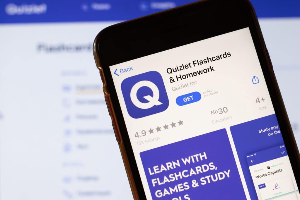 The 'Quizlet Flashcards & Homework' app on a phone screen with the Quizlet website in the background.