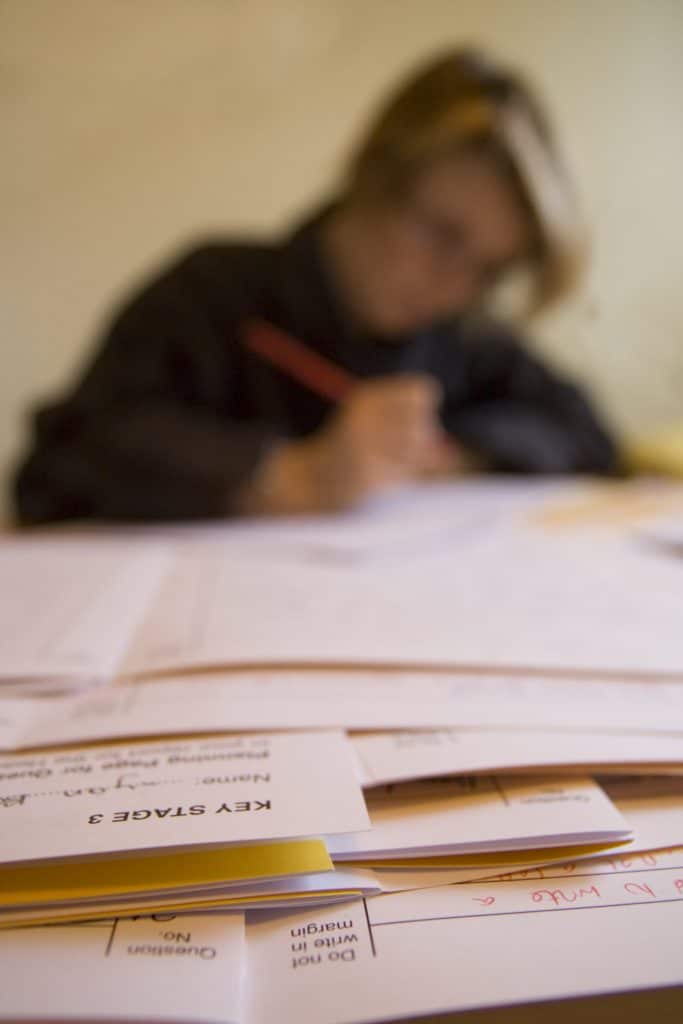 A teacher marking a pile of exam papers.