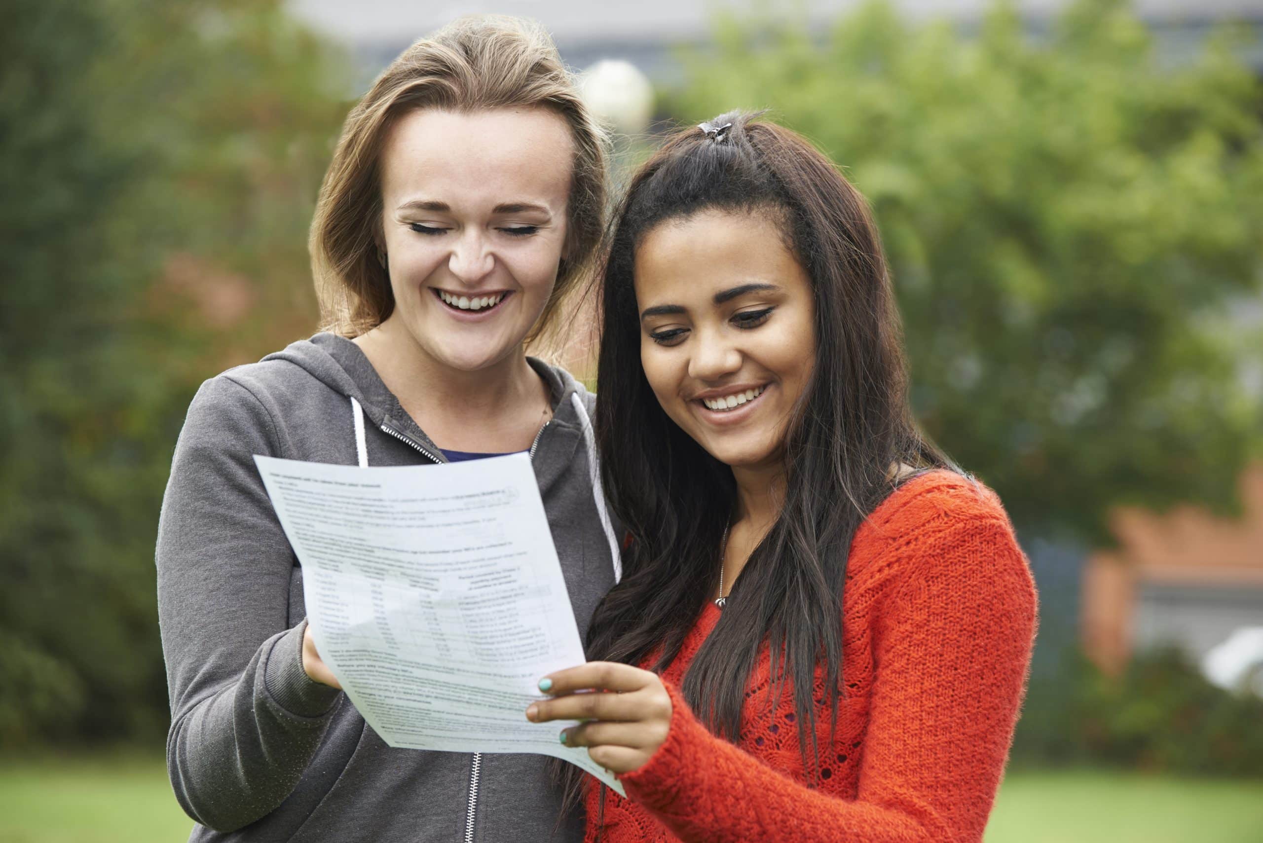 Two female students smiling at their exam results.