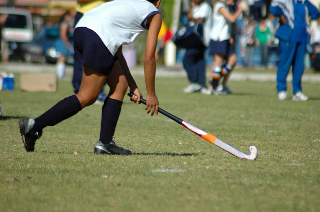 A young girl playing hockey outdoors with her team.