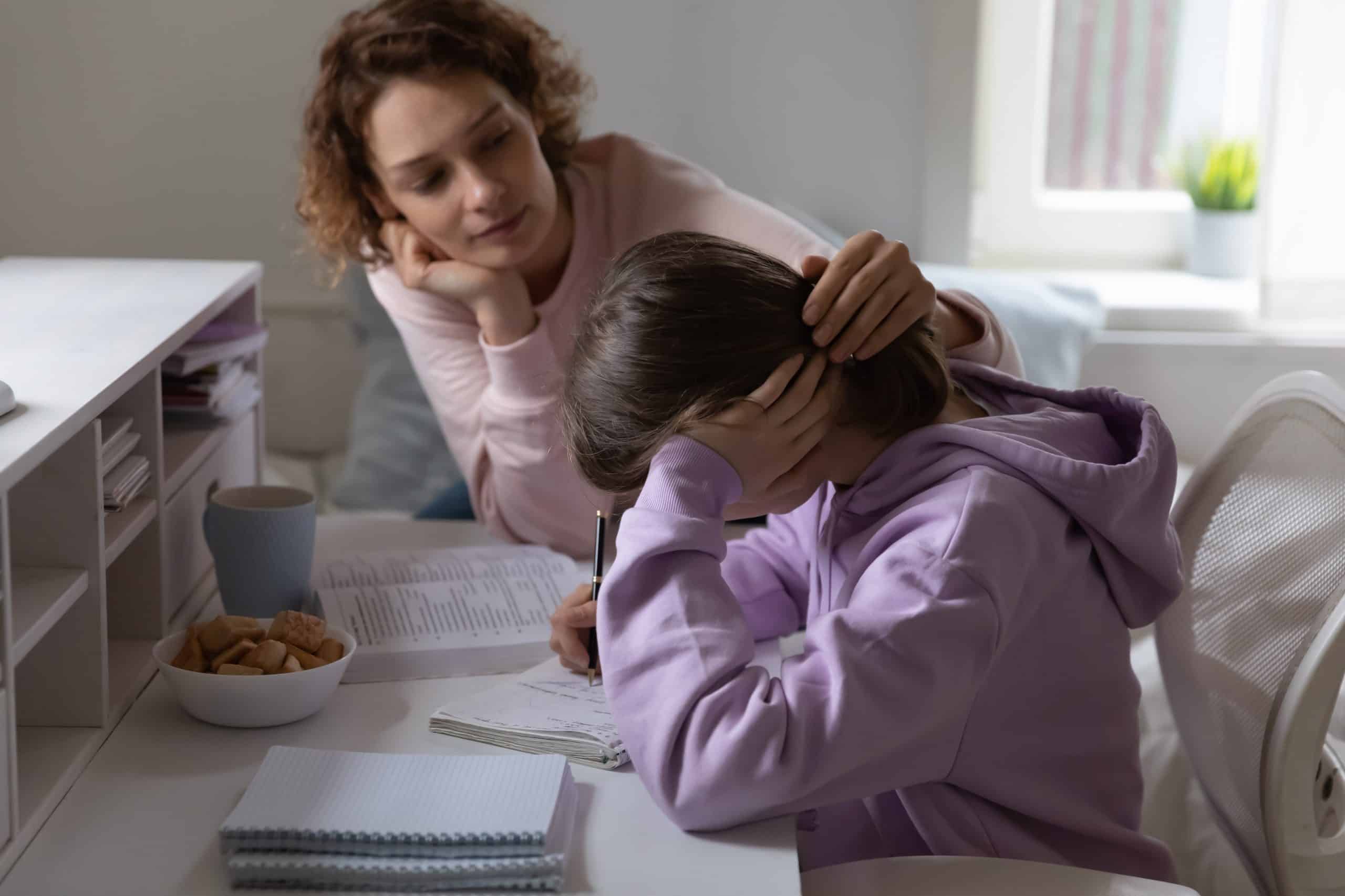 A mother supporting her stressed teenage daughter with school work.