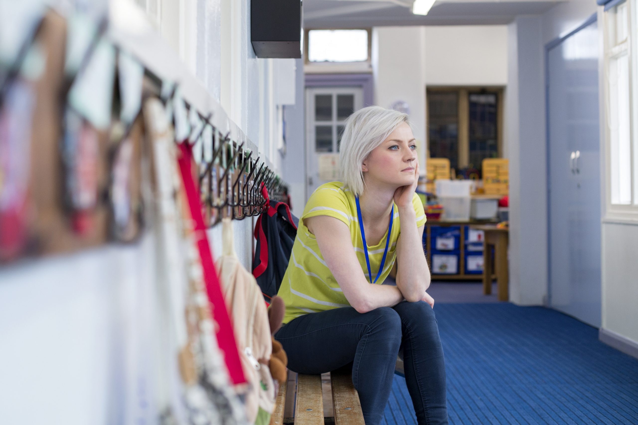 A young stressed female teacher sitting in the school cloakroom.