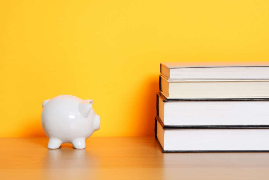 A piggy bank sitting next to a pile of books.