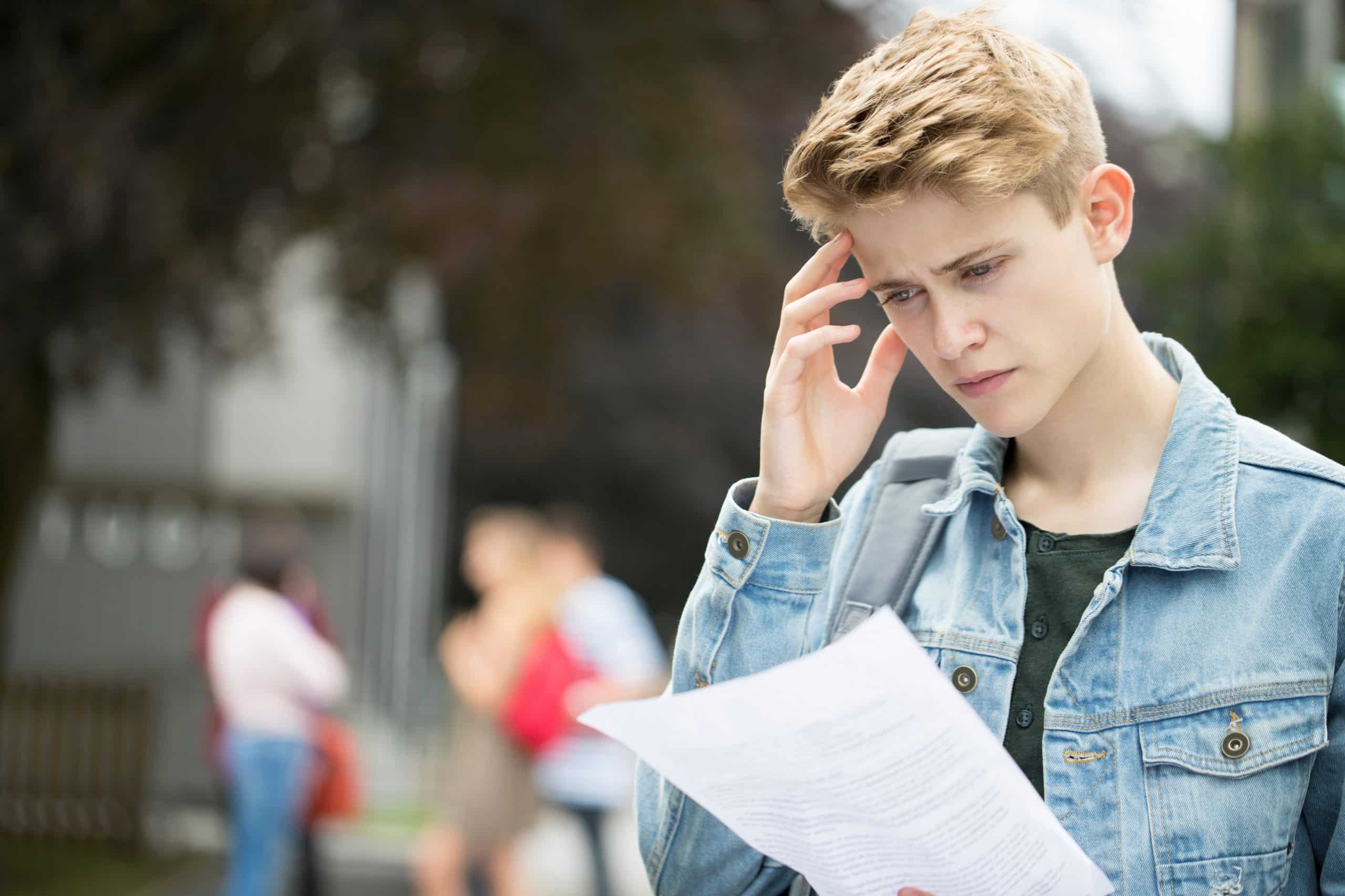 A disappointed teenage boy looking at his exam results.